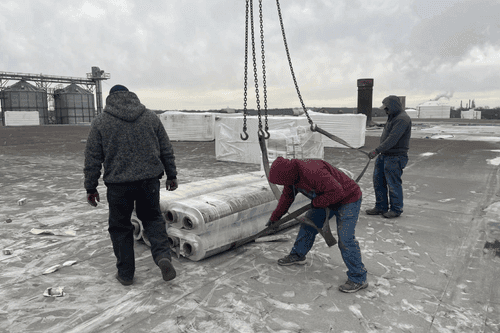 Commercial roofing crew installing roofing material on a flat commercial building