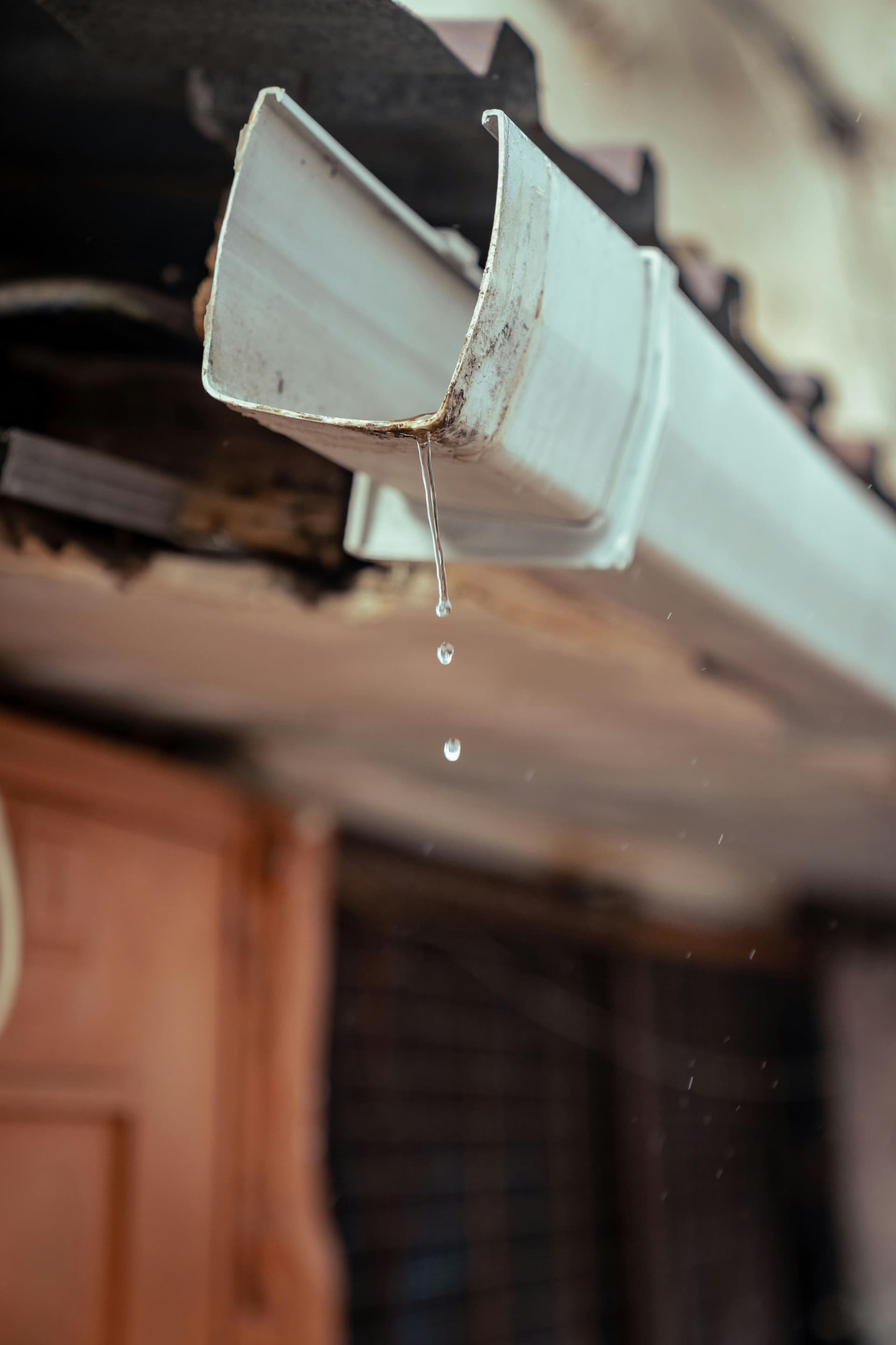 Close-up of cracked failing rain gutter with water dripping - needs replacement in Fort Worth